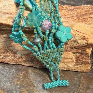 Turquoise color beaded necklace with Czech glass beads and seed beads on a stone background